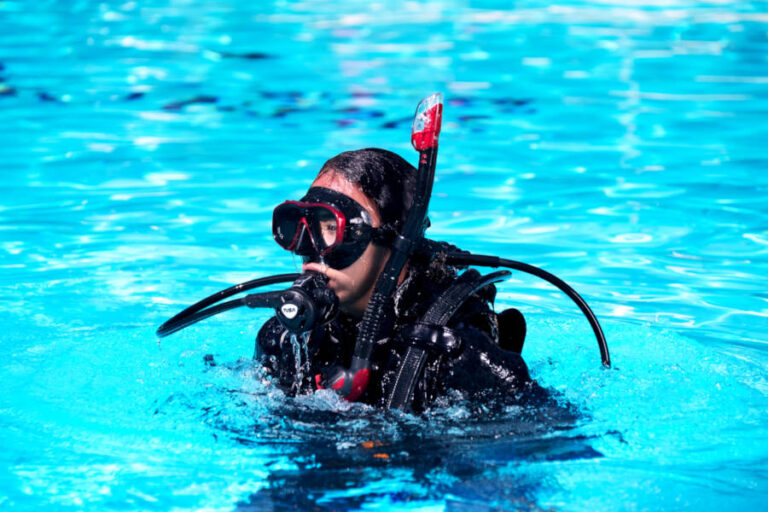 PADI Scuba diver Open Water Course, swimming pool session, student at the surface with regulator in mouth