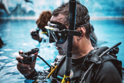 PADI Open Water Diver student in the swimming pool trying breathe with regulator