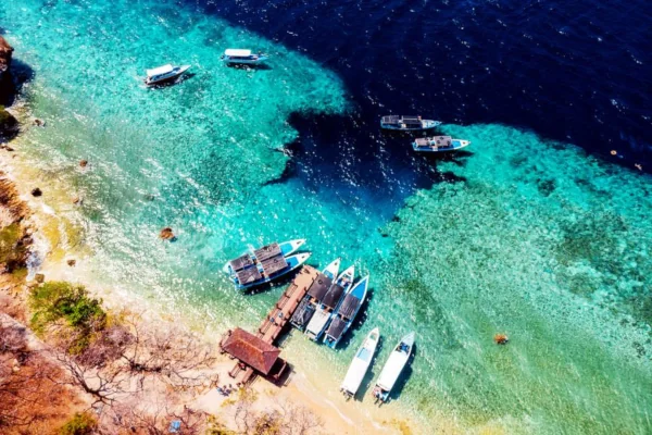 Aerial view of dive boats anchored at Menjangan Island, Bali, with clear turquoise water and coral reef below. Dive site POS 2, near Menjangan Cave