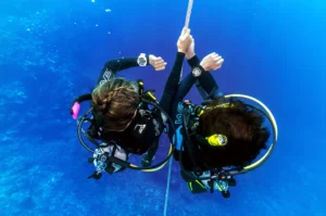 PADI Advanced Open Water course in Bali – diver at safety stop checking dive computer with reel, Bali Aqua